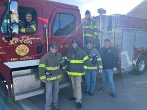 A group of firefighters standing in front of a fire truck

Description automatically generated